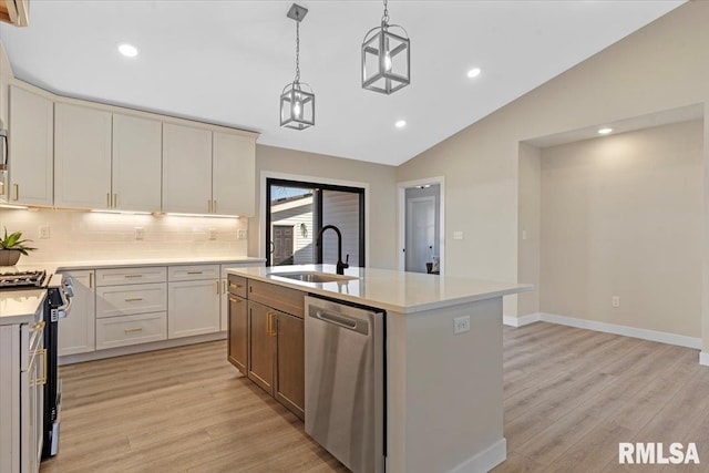 kitchen with light wood finished floors, light countertops, lofted ceiling, appliances with stainless steel finishes, and a sink