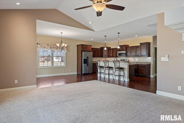 kitchen with an island with sink, dark brown cabinets, appliances with stainless steel finishes, ceiling fan with notable chandelier, and open floor plan