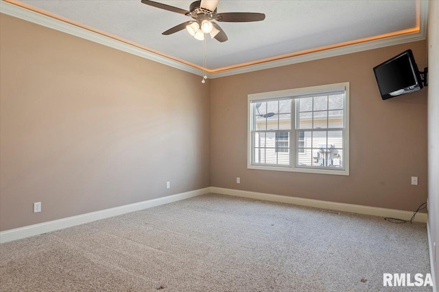 carpeted spare room with baseboards, ornamental molding, and a ceiling fan