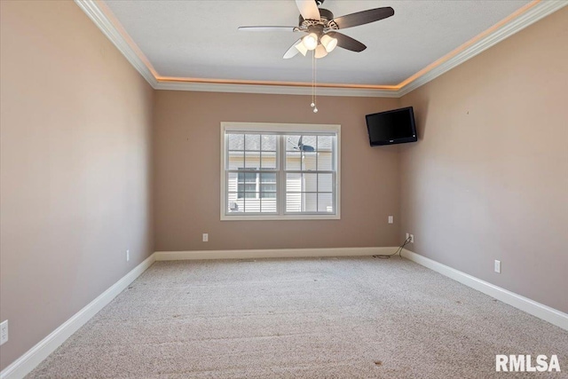 carpeted spare room featuring crown molding, baseboards, and ceiling fan