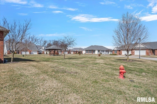 view of yard featuring a gazebo, a garage, and a residential view