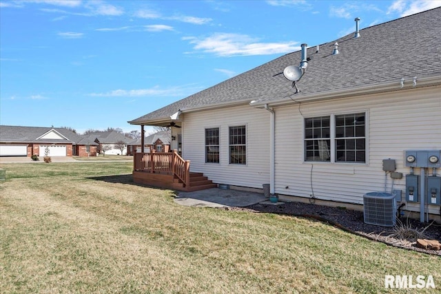 rear view of house featuring cooling unit, a yard, a deck, and a shingled roof