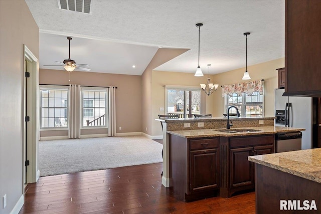 kitchen featuring visible vents, a sink, vaulted ceiling, appliances with stainless steel finishes, and ceiling fan with notable chandelier