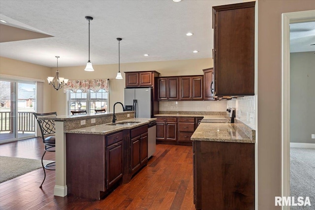 kitchen with light stone counters, a breakfast bar, a sink, appliances with stainless steel finishes, and tasteful backsplash