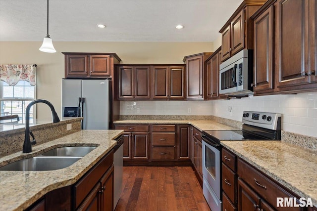 kitchen featuring a sink, tasteful backsplash, dark wood finished floors, stainless steel appliances, and light stone countertops