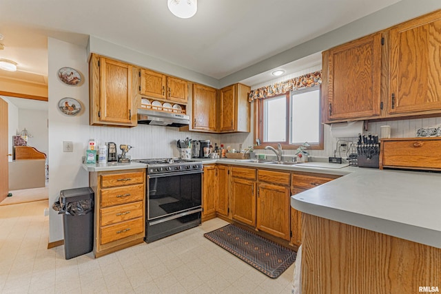 kitchen with brown cabinetry, gas stove, light floors, a sink, and under cabinet range hood