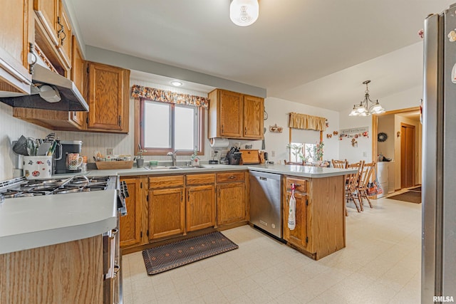 kitchen with a sink, appliances with stainless steel finishes, a peninsula, brown cabinetry, and light floors