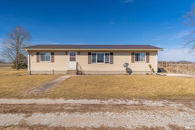 view of front of property featuring entry steps, metal roof, a front lawn, and fence