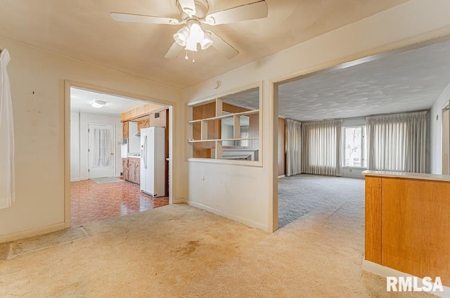 carpeted spare room with baseboards and a ceiling fan