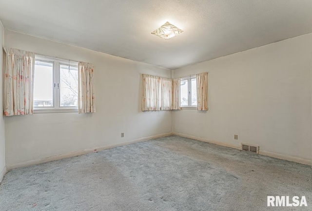 unfurnished room with visible vents, carpet floors, and baseboards