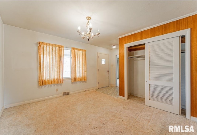 unfurnished bedroom featuring baseboards, visible vents, a closet, carpet flooring, and a chandelier