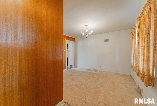 empty room featuring light carpet, visible vents, baseboards, and an inviting chandelier