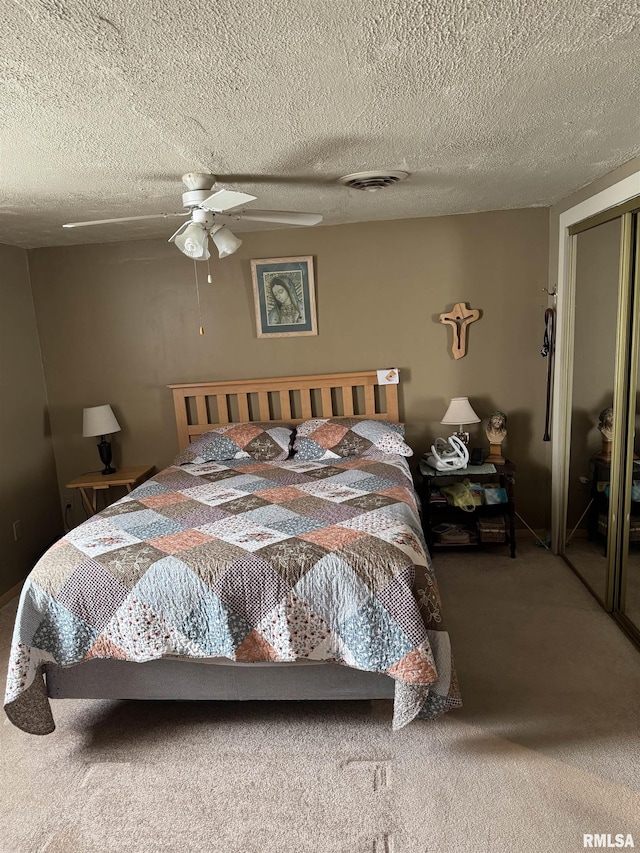 carpeted bedroom with a closet, visible vents, a textured ceiling, and ceiling fan