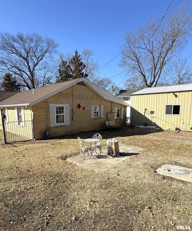 view of side of home featuring brick siding and a patio