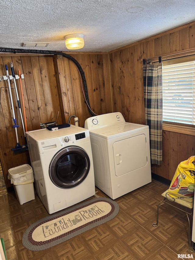 washroom with washer and dryer, wooden walls, laundry area, and a textured ceiling