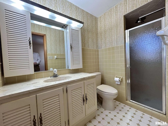 full bathroom with toilet, wallpapered walls, a shower stall, wainscoting, and vanity