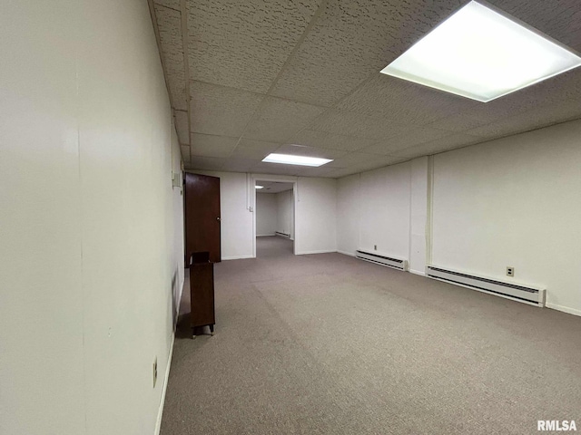 finished below grade area featuring a drop ceiling, a baseboard radiator, and carpet