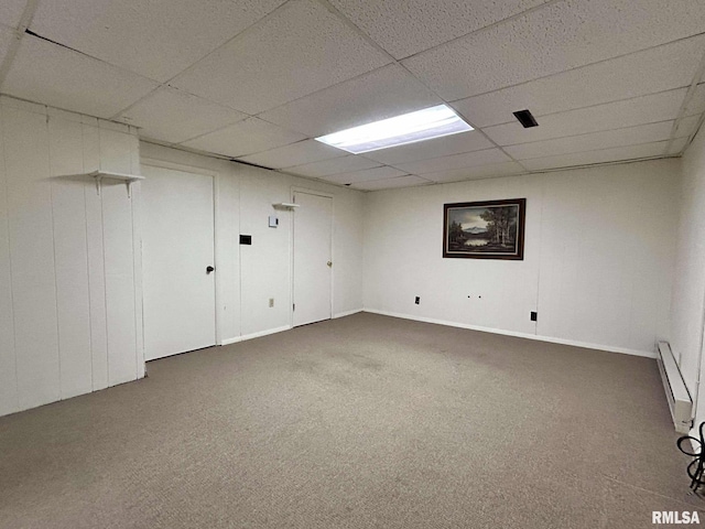 finished basement featuring a baseboard radiator, a paneled ceiling, and carpet flooring