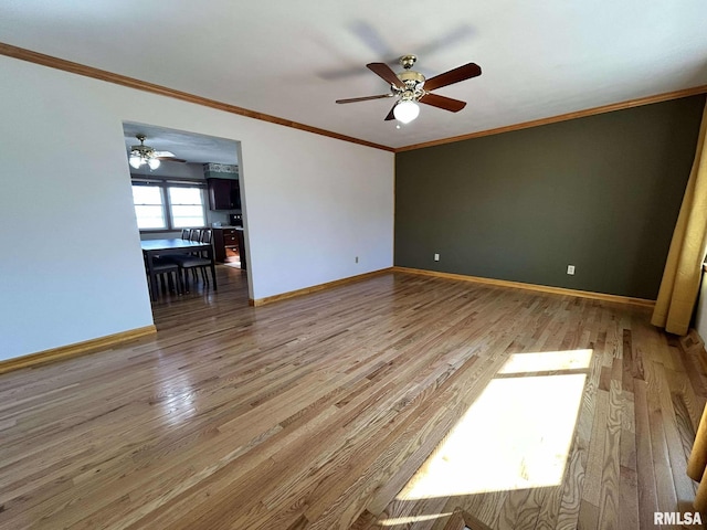 spare room featuring ceiling fan, crown molding, baseboards, and wood finished floors