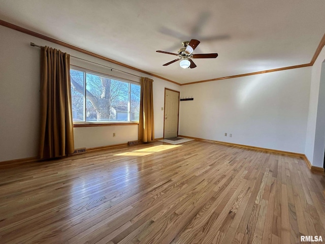 empty room featuring visible vents, ornamental molding, baseboards, and wood finished floors