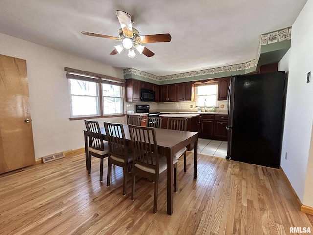 dining area featuring visible vents, light wood-type flooring, and a ceiling fan