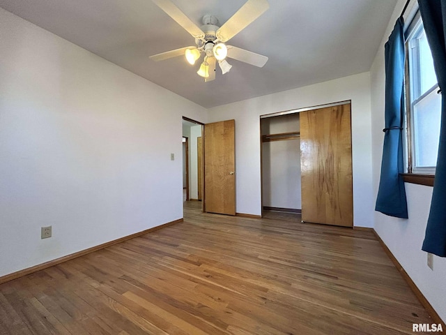 unfurnished bedroom with a closet, baseboards, wood finished floors, and a ceiling fan