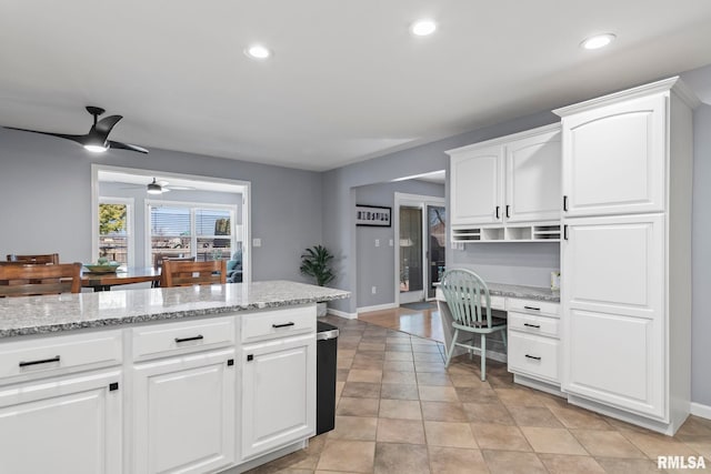 kitchen with light stone counters, built in desk, recessed lighting, and white cabinets