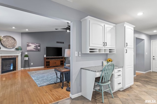 office featuring visible vents, a ceiling fan, built in desk, recessed lighting, and a fireplace