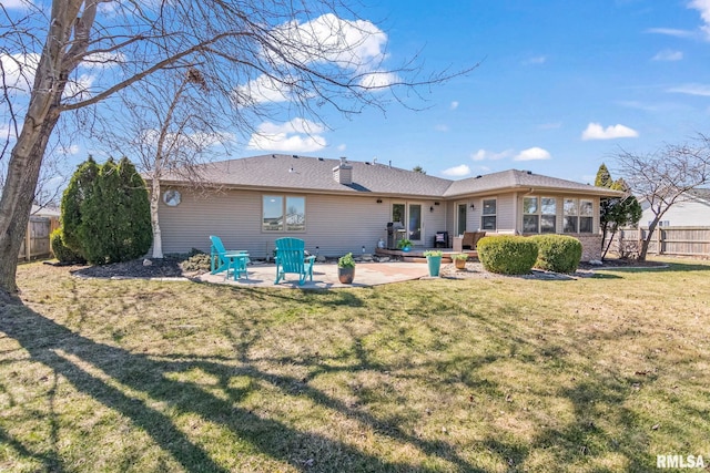 rear view of property featuring a patio, fence, and a lawn