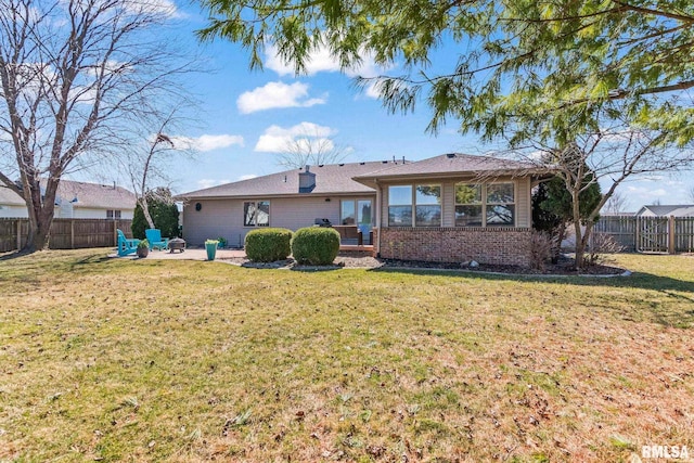 back of property with a yard, a patio area, brick siding, and a fenced backyard