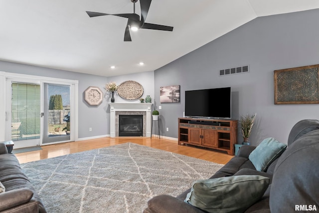 living room with visible vents, baseboards, lofted ceiling, wood finished floors, and a glass covered fireplace