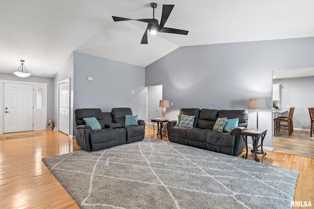 living room with baseboards, light wood-type flooring, lofted ceiling, and a ceiling fan