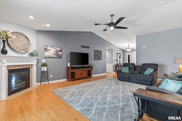 living room featuring hardwood / wood-style floors, visible vents, a fireplace, ceiling fan, and vaulted ceiling