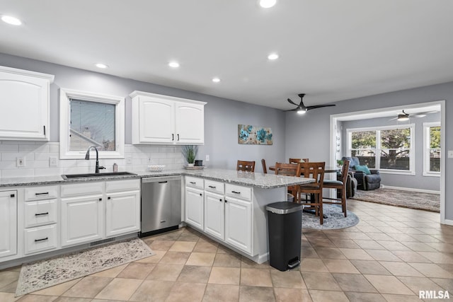 kitchen featuring tasteful backsplash, dishwasher, a peninsula, white cabinetry, and a sink