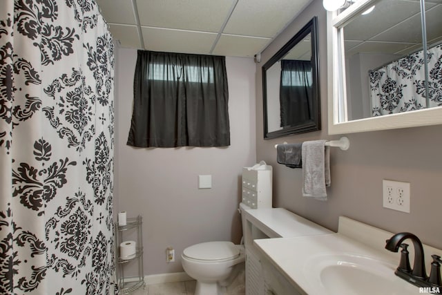 bathroom with baseboards, toilet, a shower with curtain, vanity, and a paneled ceiling