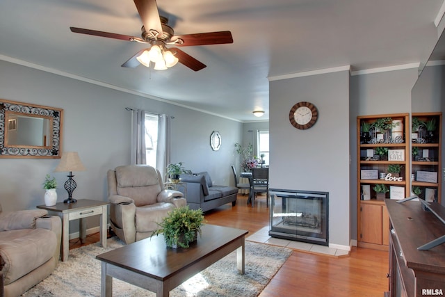 living area with light wood-style flooring, baseboards, a multi sided fireplace, and ornamental molding