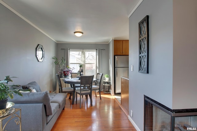 dining room featuring light wood-type flooring, baseboards, and ornamental molding