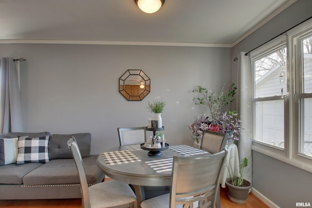 dining space featuring wood finished floors, baseboards, and ornamental molding