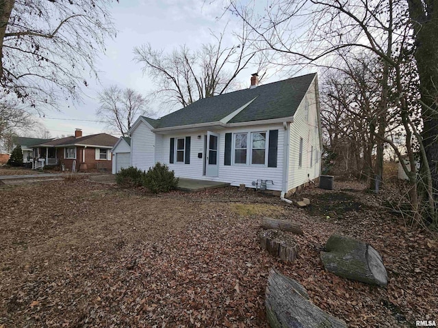 view of front facade with a chimney and a shingled roof