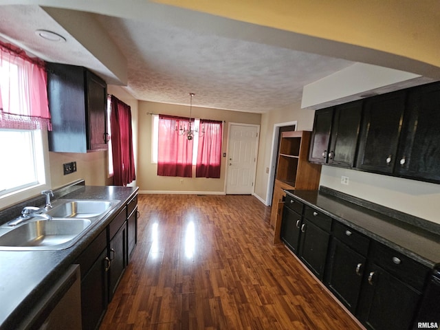 kitchen with a sink, dark wood-type flooring, stainless steel dishwasher, dark countertops, and dark cabinets