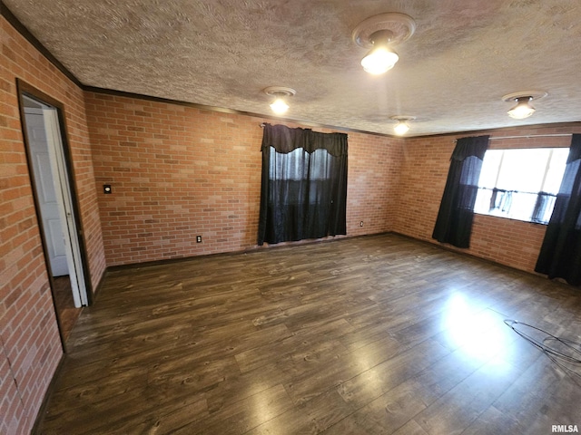 spare room with dark wood-style floors, brick wall, and a textured ceiling