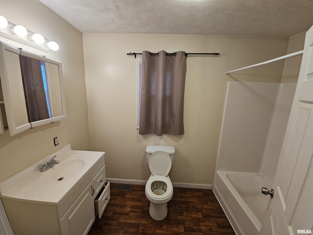 bathroom with vanity, toilet, wood finished floors, and a textured ceiling