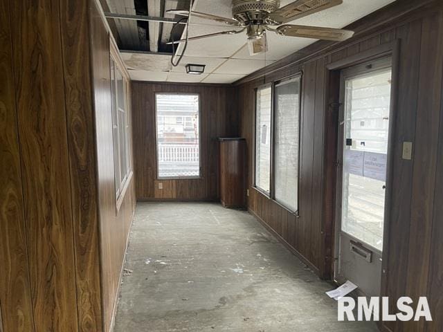 interior space featuring wood walls and a ceiling fan