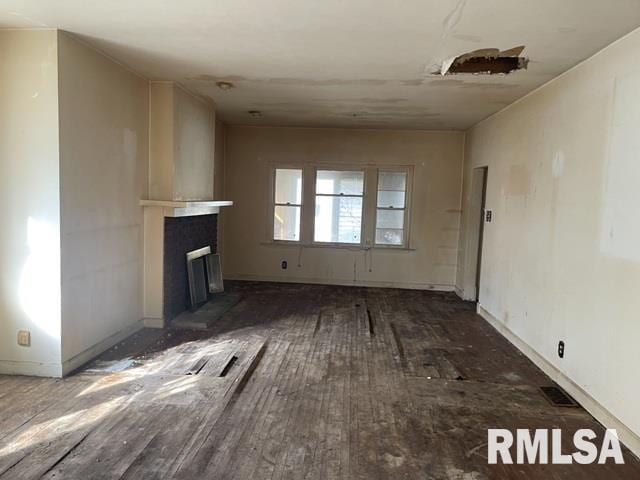 unfurnished living room featuring a fireplace with raised hearth and wood finished floors