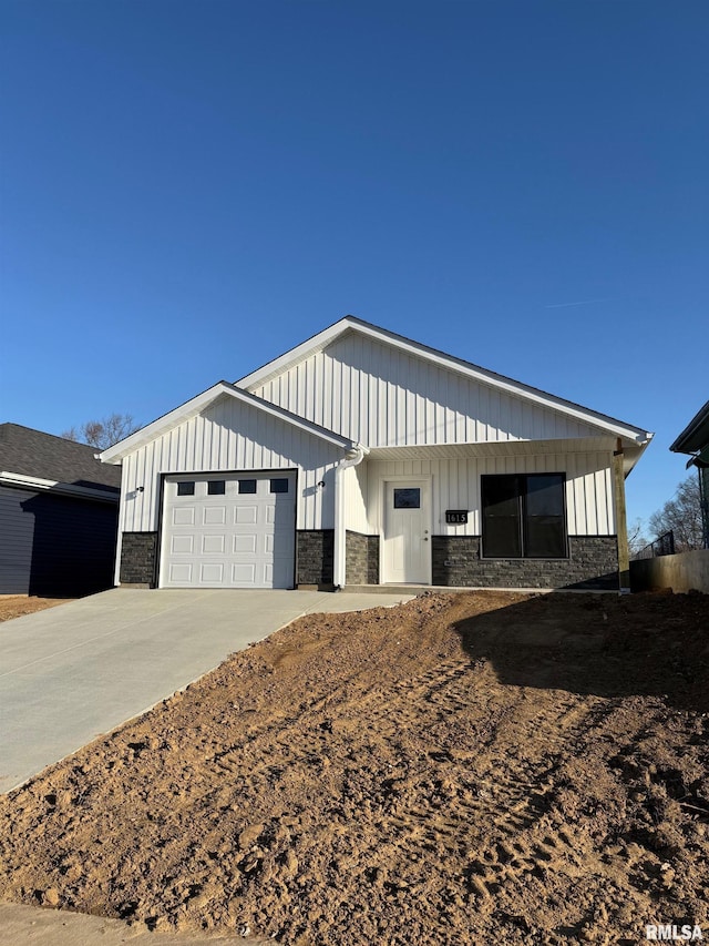 view of front of house with stone siding, board and batten siding, concrete driveway, and an attached garage