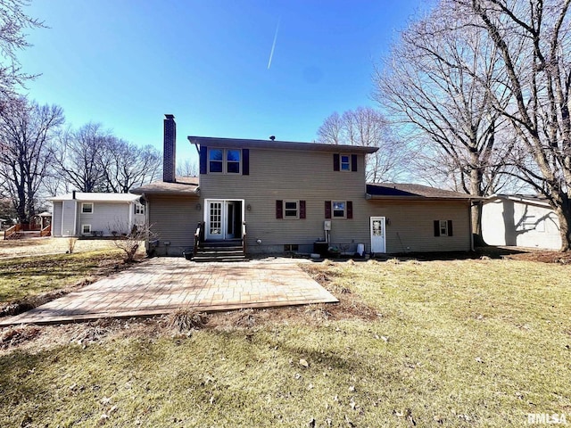 rear view of house featuring a yard, entry steps, a chimney, and a patio area