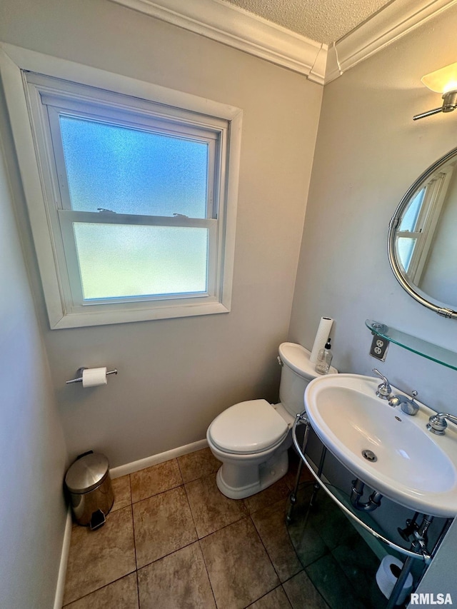 half bathroom with tile patterned flooring, toilet, baseboards, and a sink