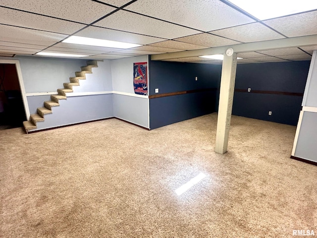 finished below grade area featuring carpet flooring, stairway, a paneled ceiling, and baseboards