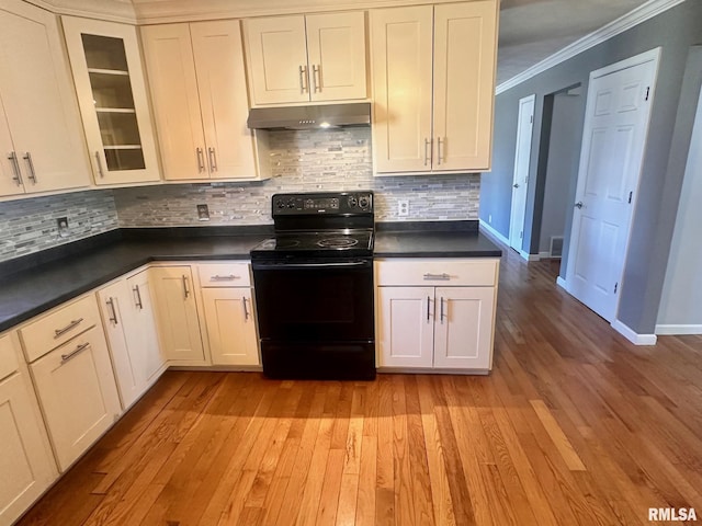 kitchen with under cabinet range hood, electric range, dark countertops, and ornamental molding