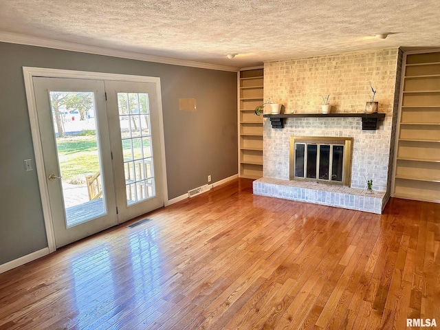 unfurnished living room featuring visible vents, a brick fireplace, crown molding, hardwood / wood-style floors, and a textured ceiling